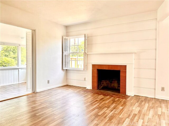 unfurnished living room with baseboards, wood finished floors, and a fireplace