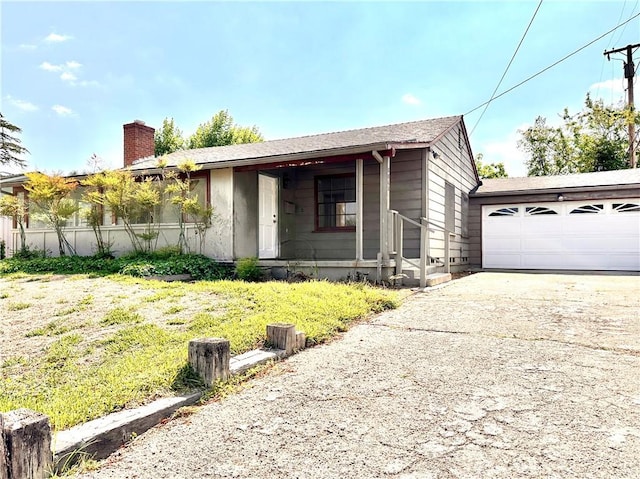 ranch-style home featuring an attached garage, driveway, and a chimney