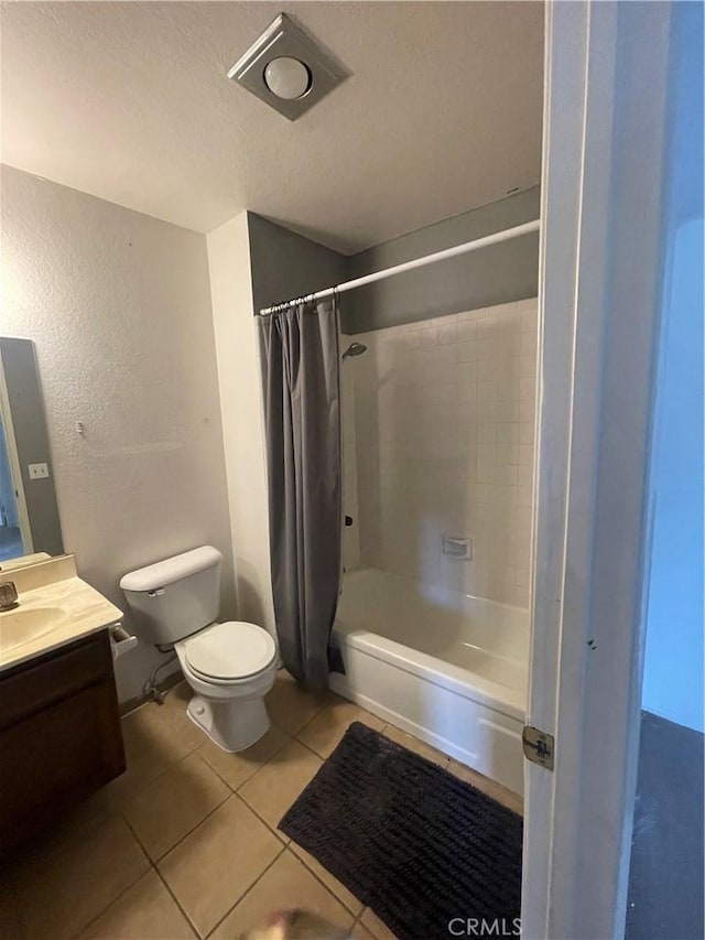 bathroom with tile patterned flooring, shower / tub combo with curtain, vanity, toilet, and a textured ceiling