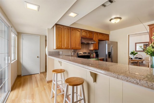 6192 Sierra Siena Rd, Irvine, CA 92603 - kitchen with visible vents, light wood-style floors, under cabinet range hood, stainless steel fridge with ice dispenser, and range with electric cooktop