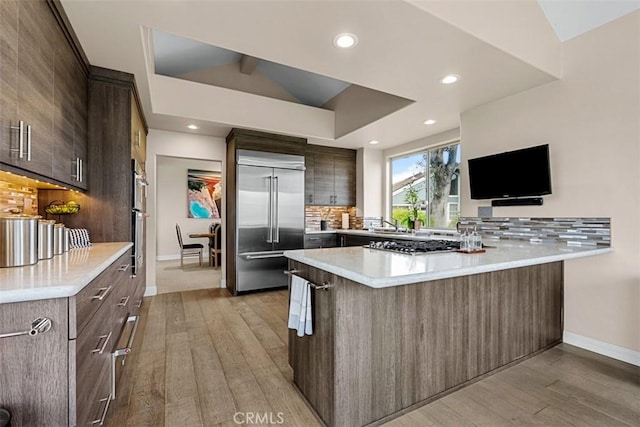 20 Delphinus Unit 20, Irvine, CA 92603 - kitchen featuring decorative backsplash, appliances with stainless steel finishes, baseboards, a peninsula, and light wood-style flooring
