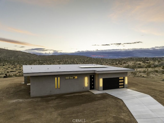 view of front of property with an attached garage, driveway, a mountain view, and stucco siding