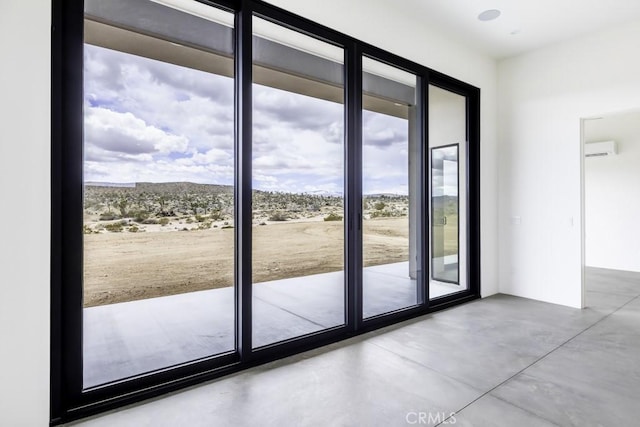 doorway with a wall mounted AC, plenty of natural light, and finished concrete floors