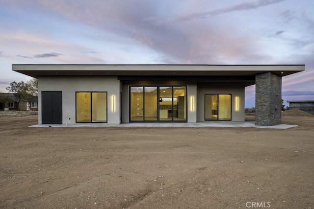 back of property at dusk with stucco siding