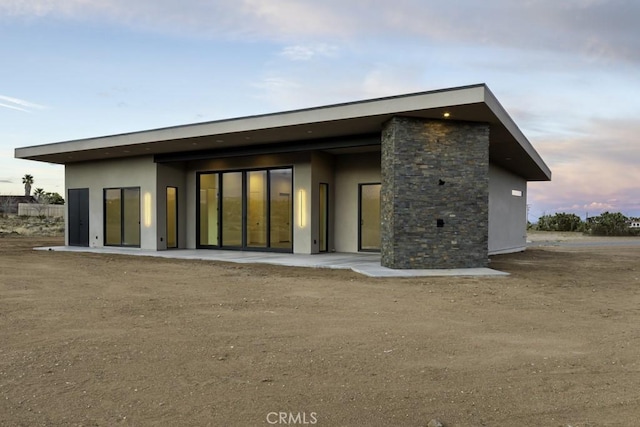 rear view of house featuring stucco siding