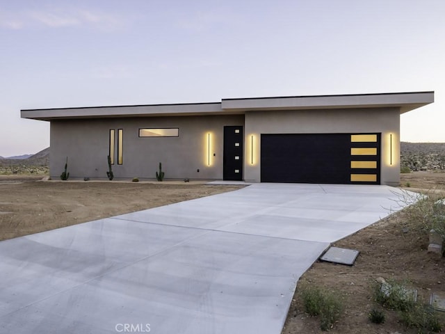 contemporary home featuring a garage, stucco siding, and concrete driveway