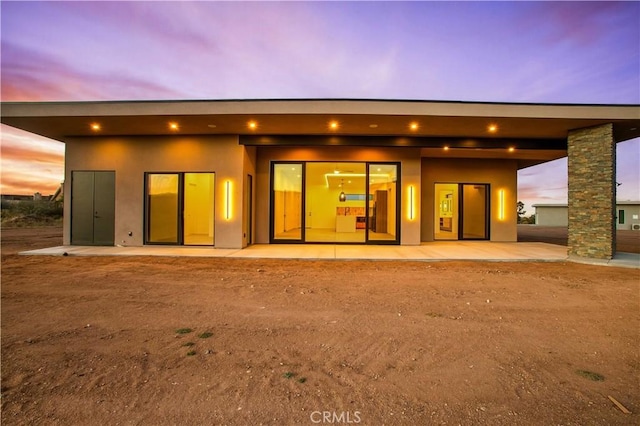 back of property with a patio and stucco siding