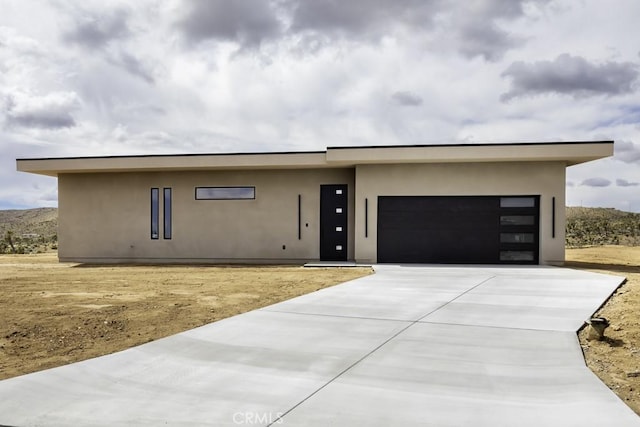 view of front facade with stucco siding, driveway, and a garage