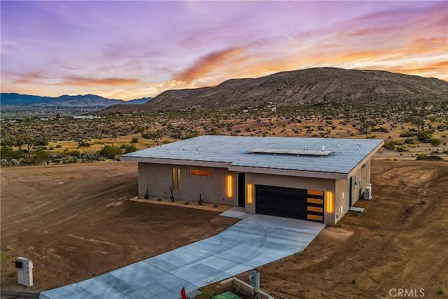contemporary home featuring driveway, solar panels, a mountain view, an attached garage, and stucco siding