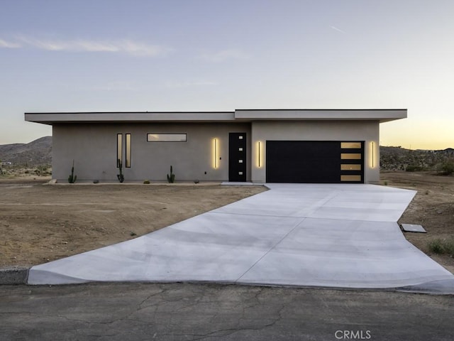 contemporary house featuring a garage, stucco siding, and driveway