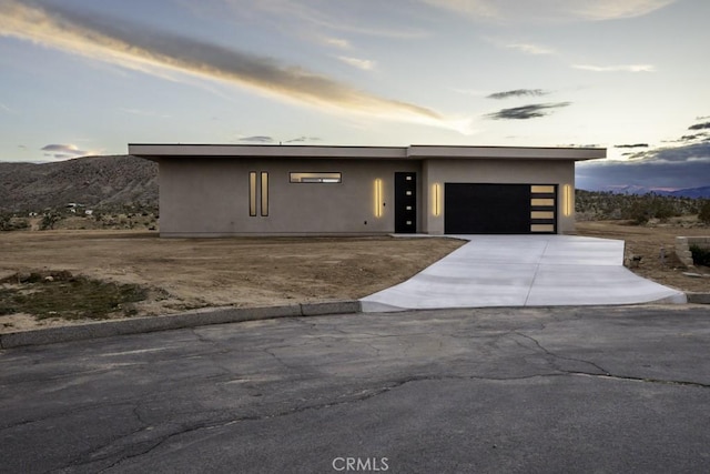 modern home with an attached garage, stucco siding, and driveway