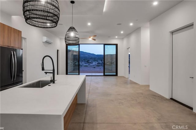 kitchen featuring freestanding refrigerator, concrete flooring, modern cabinets, brown cabinets, and a sink
