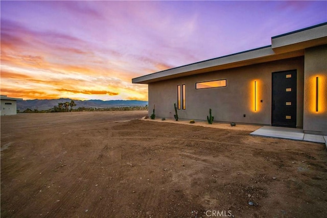 property exterior at dusk featuring a mountain view and stucco siding
