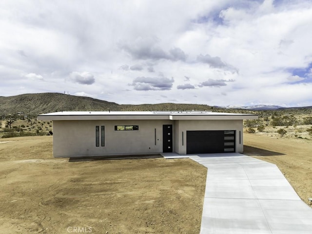 view of front of house featuring an attached garage, a mountain view, stucco siding, and concrete driveway