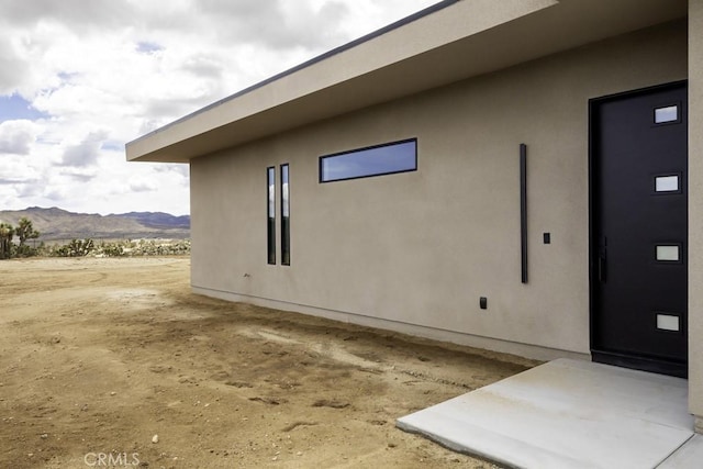view of side of property with a mountain view and stucco siding