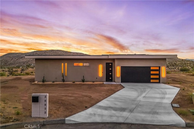 view of front of property with a garage, a mountain view, stucco siding, and concrete driveway