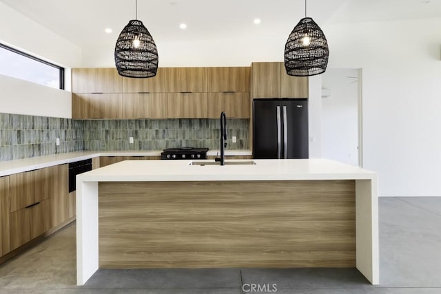kitchen with modern cabinets, tasteful backsplash, refrigerator, a sink, and concrete floors