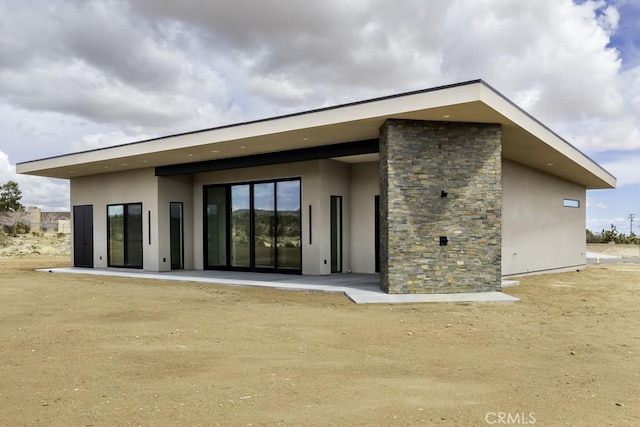 rear view of property with stone siding and stucco siding