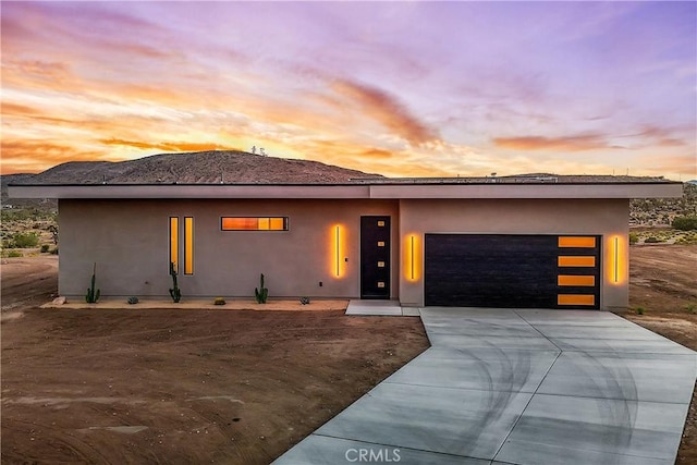 prairie-style house with an attached garage, stucco siding, and concrete driveway