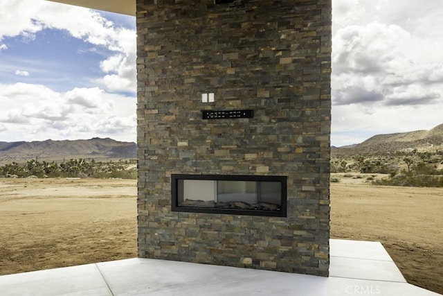 exterior space with a mountain view, an outdoor stone fireplace, and stone siding