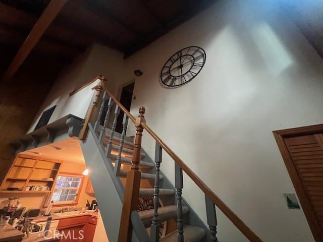 stairway featuring beamed ceiling and a high ceiling