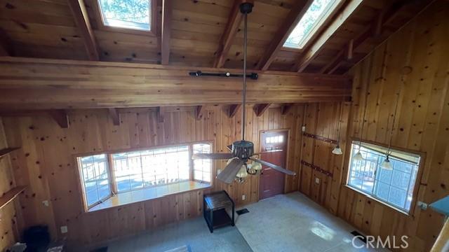 33411 Weeping Willow Dr, Green Valley Lake, CA 92341 - empty room featuring a skylight, wooden walls, wooden ceiling, beam ceiling, and carpet