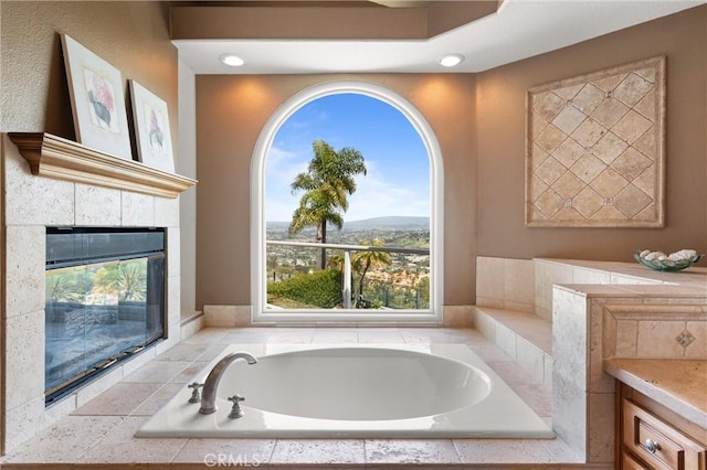 bathroom with vanity, a fireplace, a garden tub, and recessed lighting