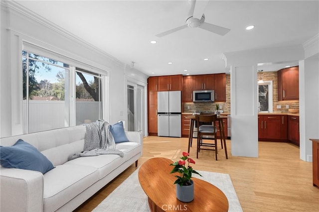 living room featuring recessed lighting, a ceiling fan, ornamental molding, and light wood-style flooring