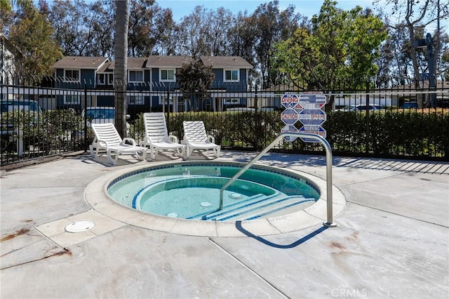 view of swimming pool featuring a hot tub and fence