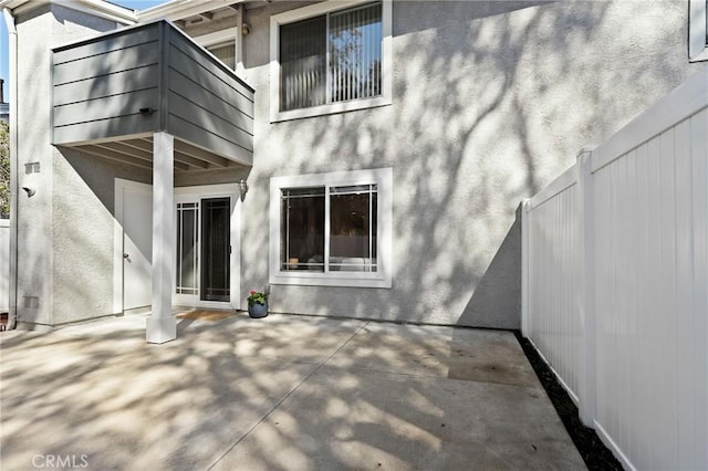 rear view of property featuring a patio area, stucco siding, and fence