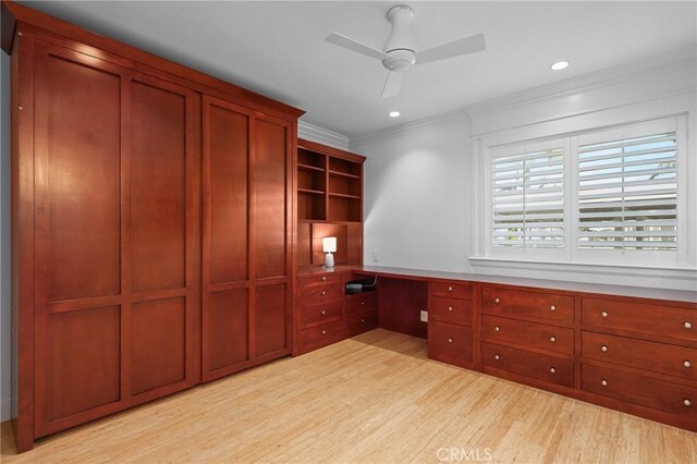 unfurnished office featuring ceiling fan, built in desk, ornamental molding, recessed lighting, and light wood-style flooring