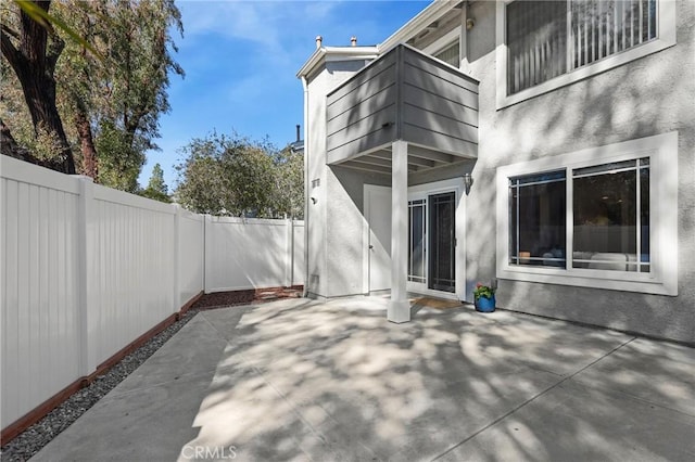 view of patio featuring fence and a balcony