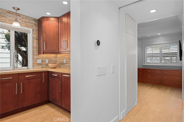 kitchen with decorative backsplash, pendant lighting, light wood finished floors, and light countertops