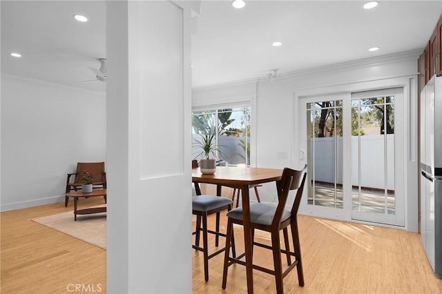 dining space featuring recessed lighting, ornamental molding, light wood-style flooring, and baseboards
