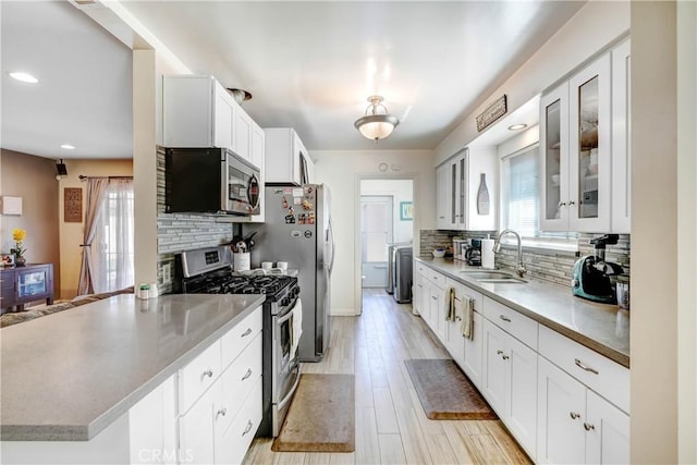 kitchen with a peninsula, appliances with stainless steel finishes, a sink, and tasteful backsplash