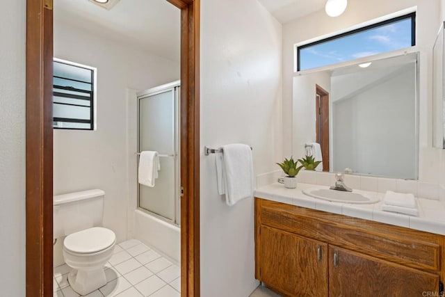 bathroom featuring vanity, enclosed tub / shower combo, tile patterned flooring, and toilet