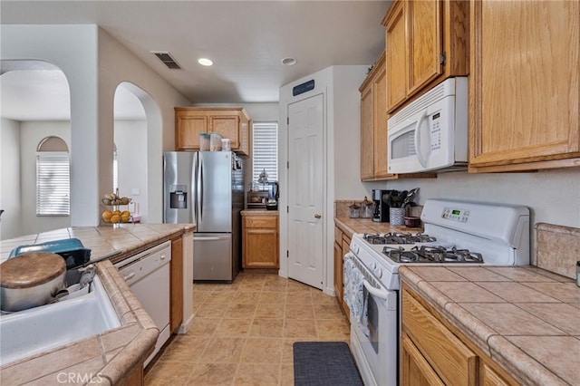 2081 Tangerine Ave, Madera, CA 93637 - kitchen featuring tile counters, white appliances, arched walkways, a sink, and recessed lighting