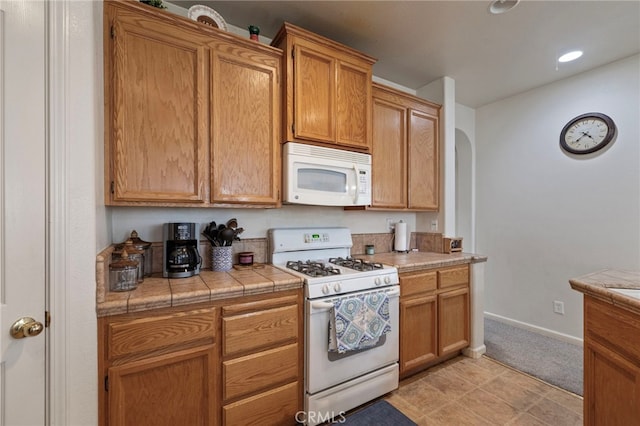 2081 Tangerine Ave, Madera, CA 93637 - kitchen with white appliances, tile counters, baseboards, arched walkways, and recessed lighting