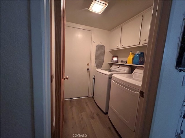 laundry room featuring independent washer and dryer, light wood-style flooring, and cabinet space