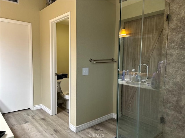 full bath featuring visible vents, a stall shower, wood finished floors, baseboards, and toilet