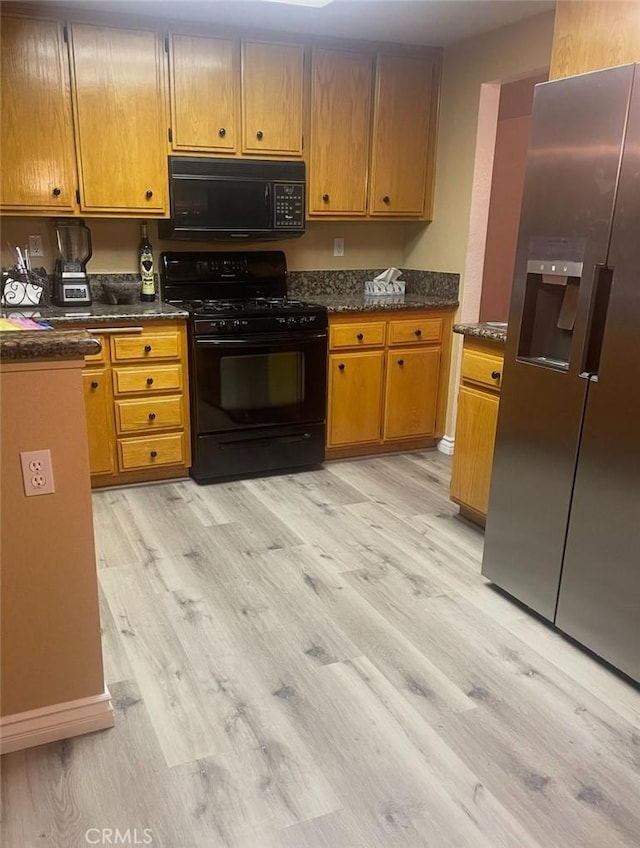 kitchen with brown cabinetry, black appliances, and light wood-style floors