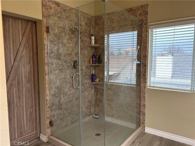 full bathroom featuring baseboards, a stall shower, and wood finished floors