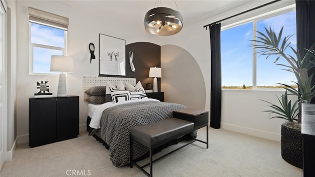 bedroom featuring a chandelier, baseboards, light colored carpet, and multiple windows