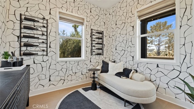 sitting room featuring baseboards, wood finished floors, and wallpapered walls