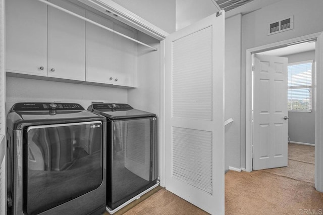 clothes washing area with visible vents, light carpet, baseboards, cabinet space, and independent washer and dryer