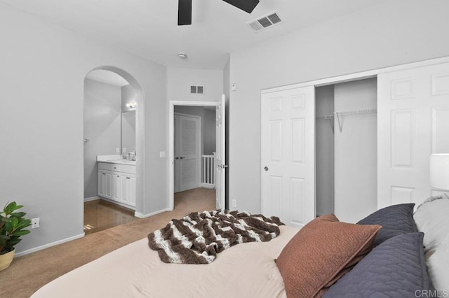 carpeted bedroom with visible vents, arched walkways, ensuite bathroom, and a closet