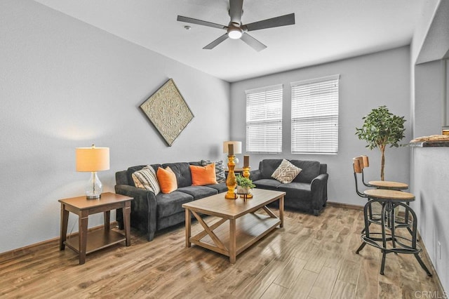 living area featuring ceiling fan, baseboards, and light wood-type flooring