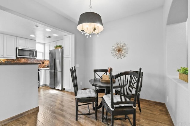 dining space with an inviting chandelier, baseboards, light wood finished floors, and visible vents