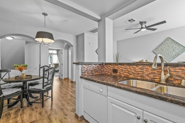 kitchen with a sink, dishwasher, arched walkways, ceiling fan with notable chandelier, and visible vents