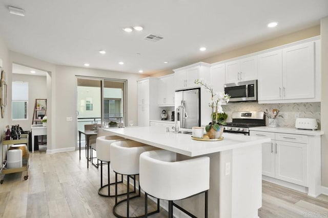 16755 Coyote Bush Dr Unit 32, San Diego, CA 92127 - kitchen with appliances with stainless steel finishes, an island with sink, light wood-style floors, white cabinets, and recessed lighting